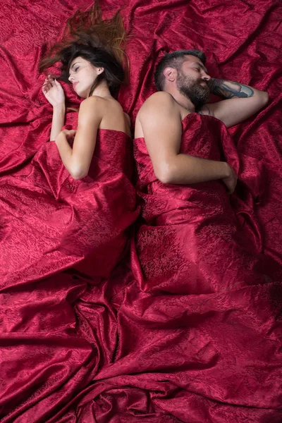 Man with beard lying back to back with pretty lady — Stock Photo, Image