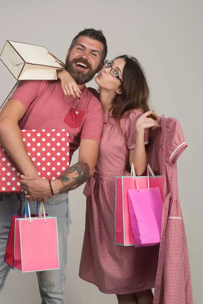 Bearded man dressed in pink smiles. Couple holding shopping bags