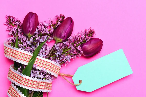 Tulips bunch and turquoise blue note tag isolated on pink