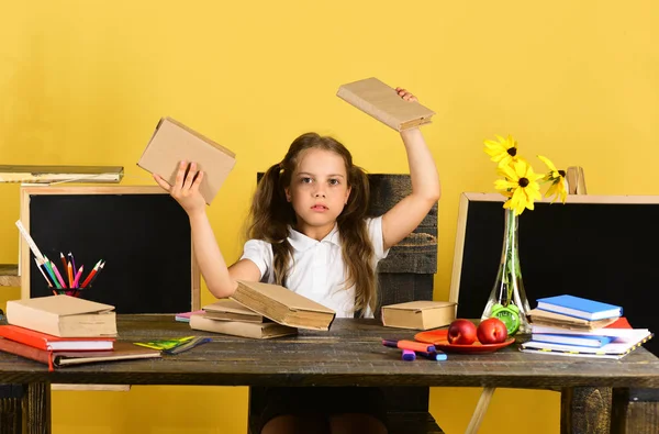 Menina senta-se na mesa de madeira com artigos de papelaria coloridos, flores — Fotografia de Stock