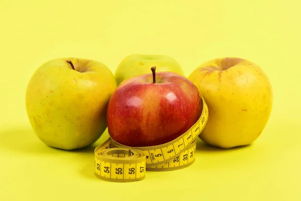 Tejp för mätning och fyra äpplen, isolerad på gul bakgrund — Stockfoto
