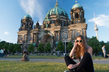 Berlin Katedrali 'nin önünde güneş kremi sürerek oturuyor.