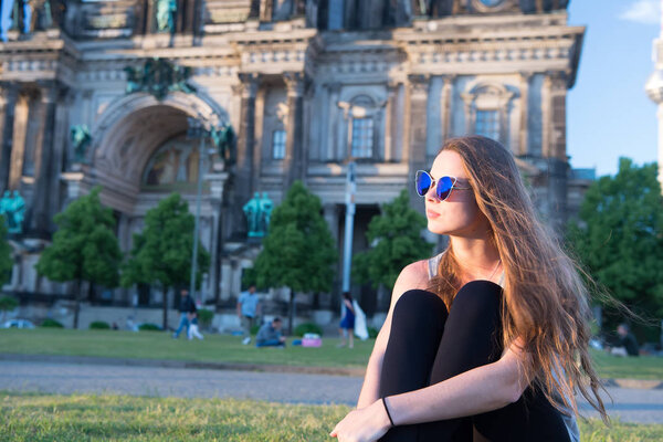Pretty gil sitting in front of Berlin Cathedral wearing sunglusses