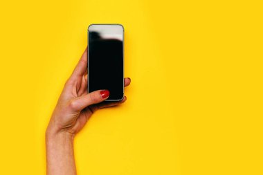 Kız dokunmatik cep telefonu ekran sarı arka plan üzerinde el ile