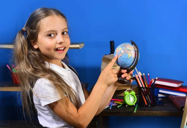 A rapariga está ao lado da secretária com livros. Material escolar e infantil — Fotografia de Stock