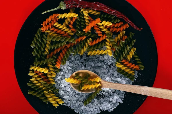 Plate with pasta, salt, chili pepper and spoon — Stock Photo, Image