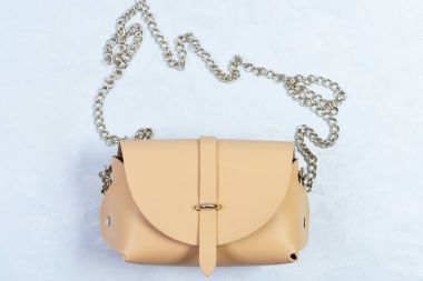 Açık mavi renkli üzerinde rahat bej deri çanta.