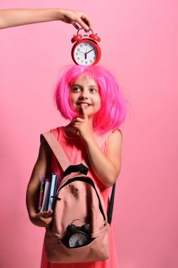 Okul üniformalı, başında peruk ve alarm olan bir öğrenci.