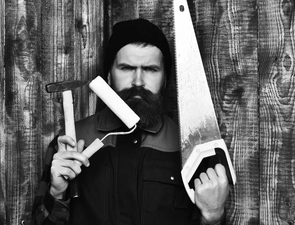 Bearded man holding various building tools with serious face — Stock Photo, Image
