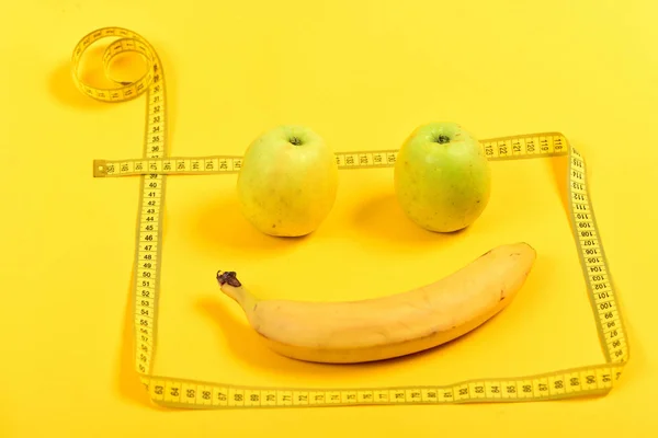 Emoticon made of apples and banana with tape for measuring — Stock Photo, Image