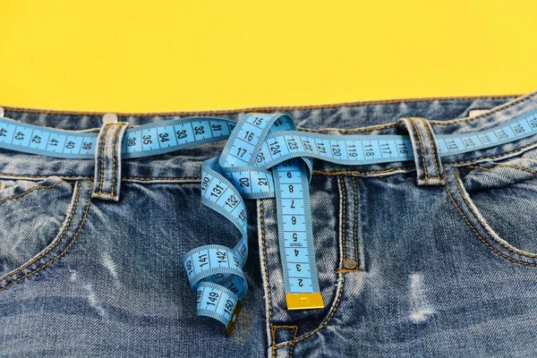 Jeans com fita métrica em torno da cintura como cinto, close-up — Fotografia de Stock