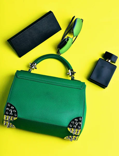 Small womans leather green bag with sunglasses, perfume and case — стоковое фото