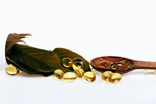 Fish oil omega 3 gel capsules in spoon with leaves — Stock Photo, Image