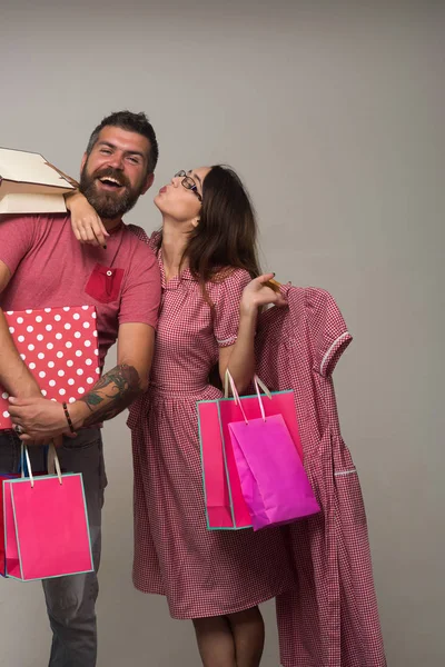 Hombre barbudo vestido con sonrisas rosas. Pareja sosteniendo bolsas de compras —  Fotos de Stock