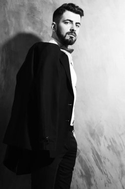 Stüdyo duvarında ciddi bir yüzü olan sakallı bir adam.