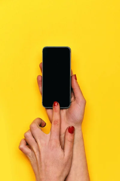 Girl touch mobile phone screen with hand on yellow background — Stock Photo, Image