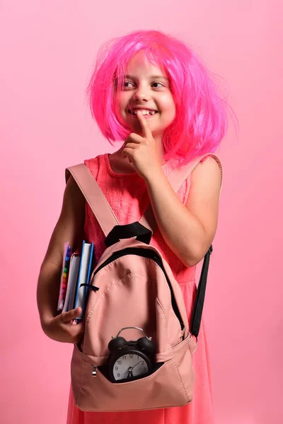 School girl with thoughtful face and smile wears backpack