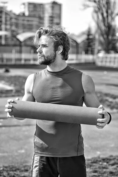 Hombre con cuerpo muscular, barba sosteniendo yoga o colchoneta de fitness — Foto de Stock