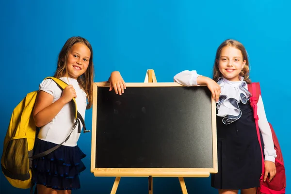 Écolières avec des visages souriants se tiennent près du tableau noir — Photo