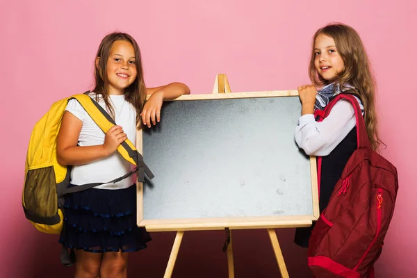 Écolières avec des visages souriants se tiennent près du tableau noir — Photo