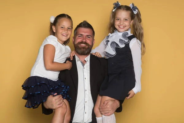 Father with beard and happy face holds schoolchildren