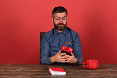 Öğretmen merak yüz ile tahta masada oturur