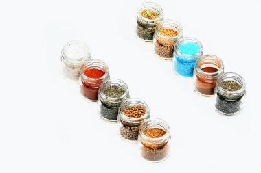 beyaz zemin üzerine kavanoz içinde çeşitli baharatlar