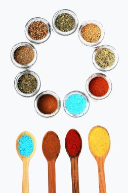 kaşık ve beyaz zemin üzerine kavanoz içinde çeşitli baharatlar