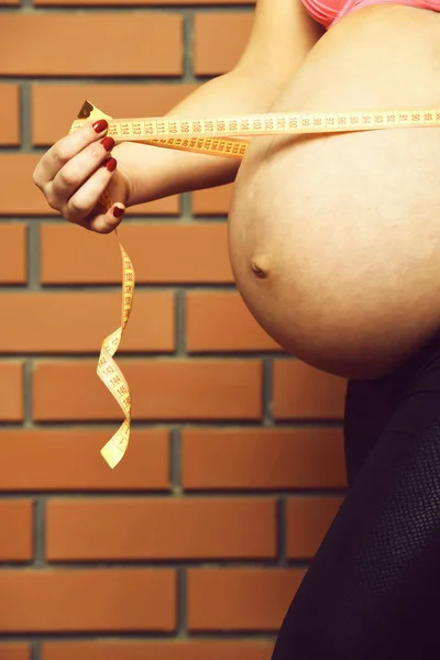Vrouw buik van zwanger naakt vrouw in zwart vacht — Stockfoto