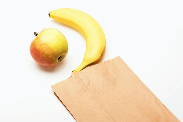 Banana e mela in confezione di carta isolata su bianco — Foto Stock