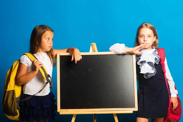 Kinder halten große Schulranzen in der Hand, kopieren Platz. Schülerinnen mit ernsten Gesichtern — Stockfoto