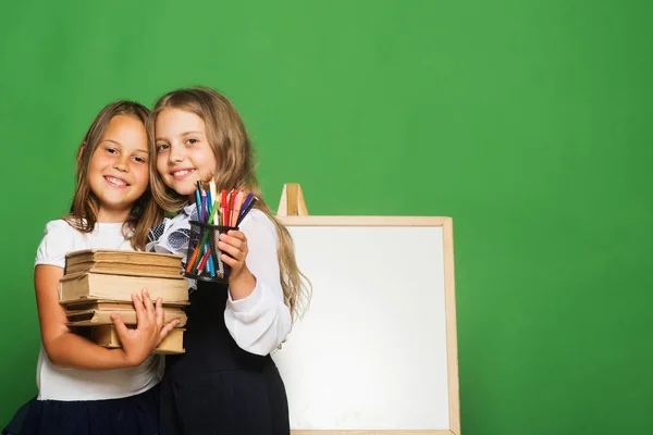 Kinder halten Stapel Bücher und ein Bündel Bleistifte in der Hand — Stockfoto