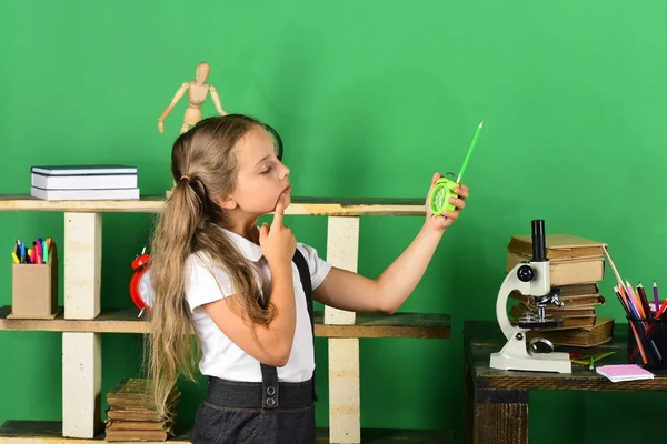 Material infantil e escolar em fundo verde. Menina segura relógio — Fotografia de Stock