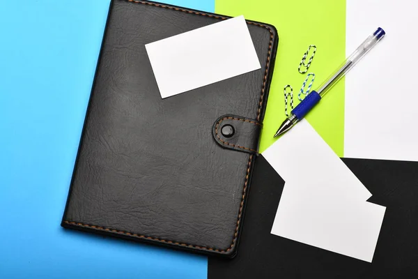 Notebook, pen, blank business cards, and clips on colourful surf — Stock Photo, Image
