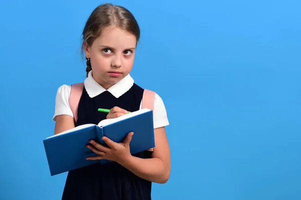 School girl with thoughtful face isolated on blue background — Stock Photo, Image