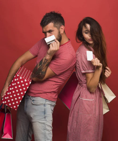 Pareja enamorada sostiene bolsas de compras, muestra tarjetas de crédito —  Fotos de Stock