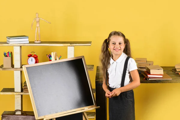 Menina em sala de aula fica perto de quadro-negro, espaço de cópia — Fotografia de Stock