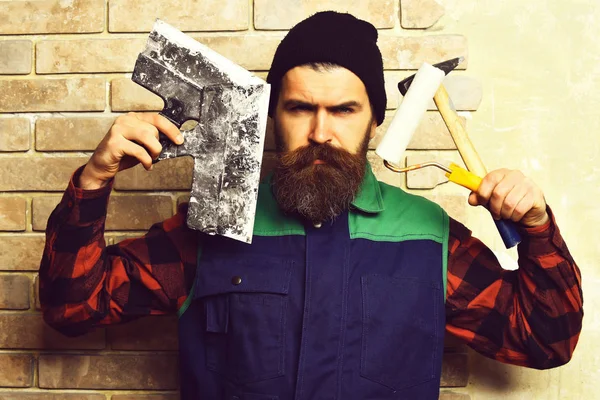 Бородатый строитель держит различные строительные инструменты с серьезным — стоковое фото