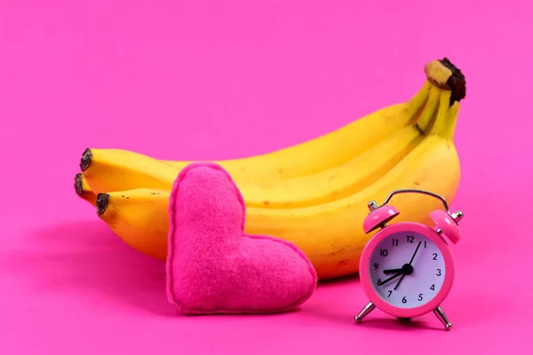 Τσαμπί μπανάνες δίπλα στο ξυπνητήρι και καρδιά — Φωτογραφία Αρχείου