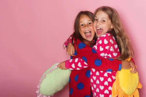 Dziewczyny w kolorowych polka notacji piżamy posiadają zabawne poduszki — Zdjęcie stockowe