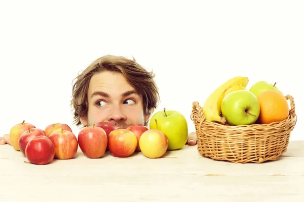 Hombre mirando a un lado con astuta sonrisa detrás de las manzanas — Foto de Stock