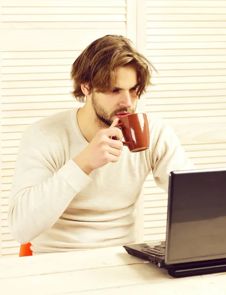 Man at his working place with gadget and tea cup