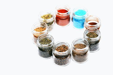 beyaz zemin üzerine kavanoz içinde çeşitli baharatlar