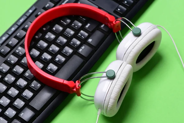 Headphones and black keyboard. Earphones in red and white colors