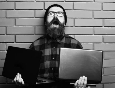 Kaba sakallı, beyaz tenli hippi dizüstü bilgisayar tutuyor.