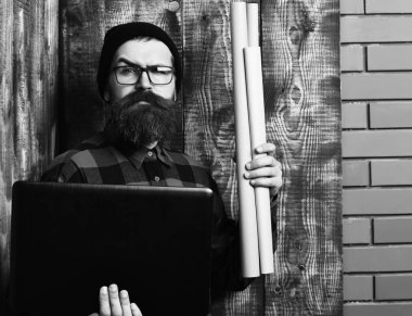 Kaba sakallı, beyaz tenli hippi elinde dizüstü bilgisayar ve el işi kâğıdı tutuyor.