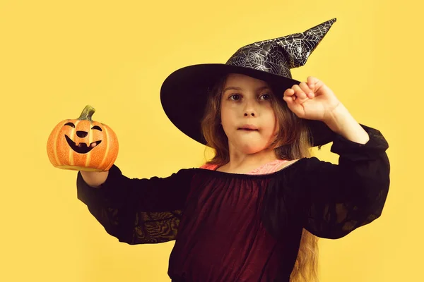 Chica con calabaza naranja tallada aislada en el fondo amarillo cálido — Foto de Stock