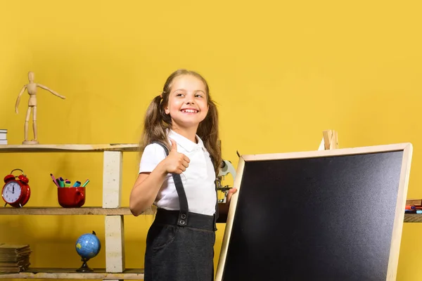 Kinder- und Schulbedarf, gelber Hintergrund. Schulmädchen mit fröhlichem Gesicht — Stockfoto