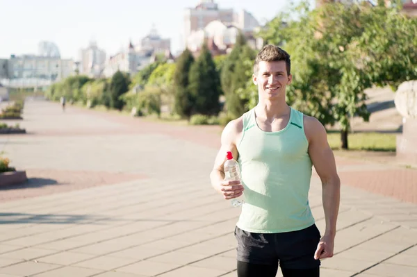 Gelukkig man atleet glimlachend met flesje water — Stockfoto