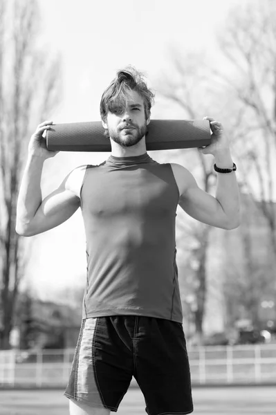Joga, fitness Mata niebieski kolor w rękach muskularny mężczyzna — Zdjęcie stockowe